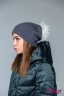 Модная женская шапка-ушанка Naumi 18 W 320 02 00 Antra – Серый​ из коллекции NAUMI зима 2018-2019. Шапка вязаная - 100% шерсть мериноса. Помпон съемный, меховой, отделка - Арктический енот. Вид сбоку 4