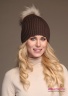 Модная женская шапка-ушанка Naumi 18 W 320 02 00 Camel – Коричневый​ из коллекции NAUMI зима 2018-2019. Шапка вязаная - 100% шерсть мериноса. Помпон съемный, меховой, отделка - Арктический енот. Вид спереди